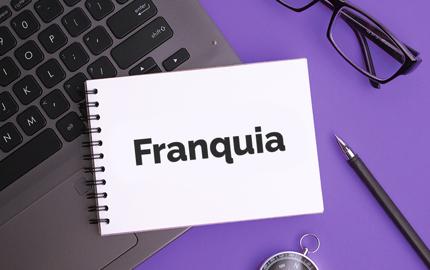 Um notebook, om um caderno escrito "Franquia" e um óculos em volta para ilustrar o tema franquias 2023.